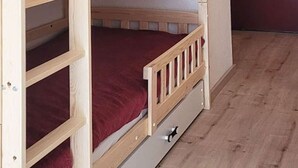 Una cama litera con colchón rojo y estructura de madera.