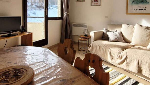 Una habitación acogedora con cama, sofá, televisión y ventana con vistas a montañas.
