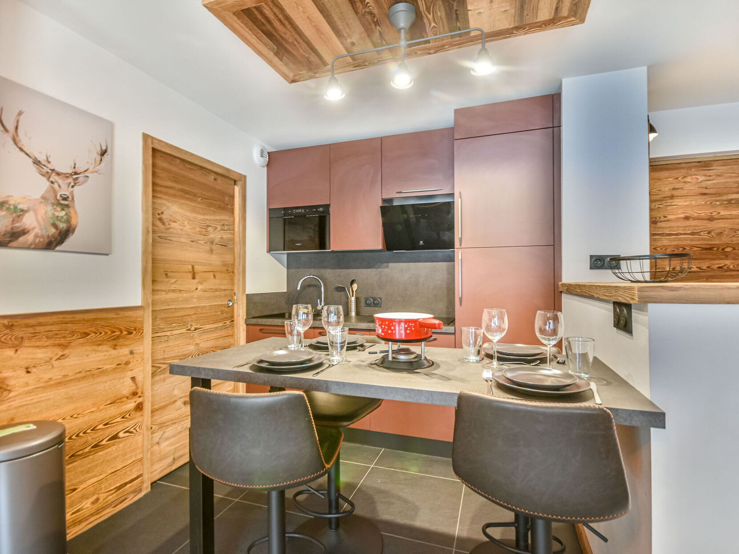 Una cocina moderna con detalles de madera, un comedor con dos taburetes y una isla de cocina.