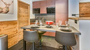 A modern kitchen with wooden accents, a dining area with two stools, and a kitchen island.