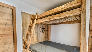 A bunk bed with a wooden ladder, a small shelf, and a power outlet.
