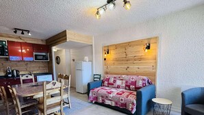 A compact living space with a kitchenette, a dining area, and a sofa.