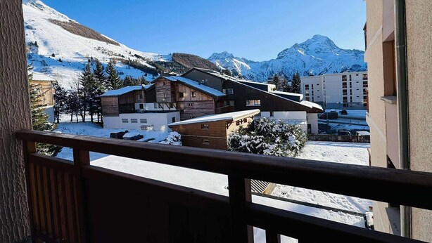 A snow-covered mountain village with wooden buildings and a clear blue sky.