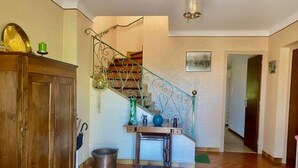Un vaste espace de vie agrémenté d’un meuble en bois, d’un escalier doté d’une rampe en métal et d’un vase vert posé sur une petite table.