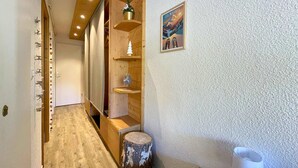 Ein hölzerner Flur mit eingebauten Regalen, einem kleinen Baumstumpf und einem gerahmten Bild an der Wand.