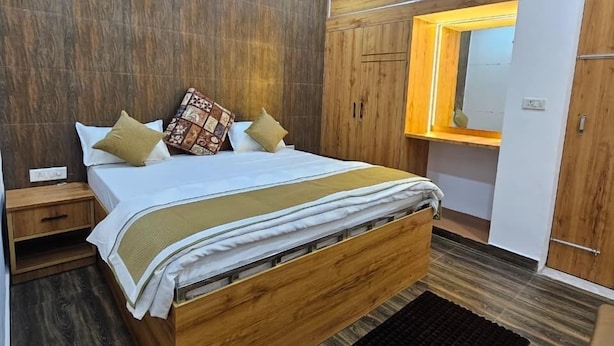Un dormitorio con una cama de madera, una mesita de noche, un tapete negro y un armario con espejo.