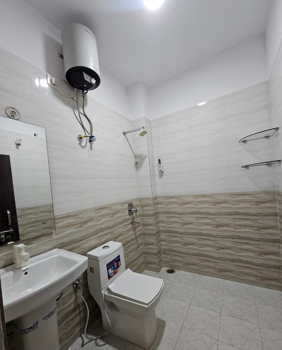 Uma casa de banho moderna com chuveiro, sanita e lavatório.