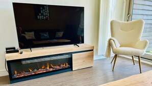 A modern living room with a flat-screen TV, a built-in fireplace, a comfortable armchair, and a wooden coffee table. - Appartement-pied des pistes -T3 -60 m2 -Garage _ Free WFI - Resort center (Les Deux Alpes)