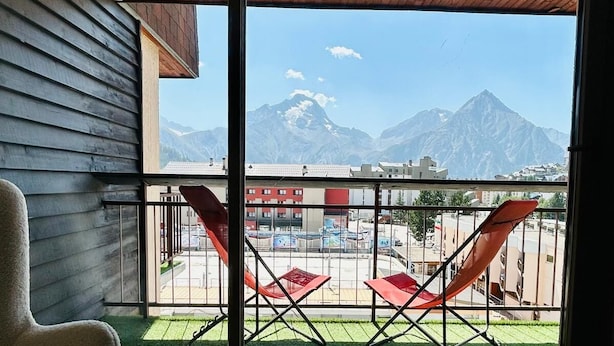 A balcony with a view of mountains, a chair, and a table with red cushions. - Appartement-pied des pistes -T3 -60 m2 -Garage _ Free WFI - Resort center (Les Deux Alpes)