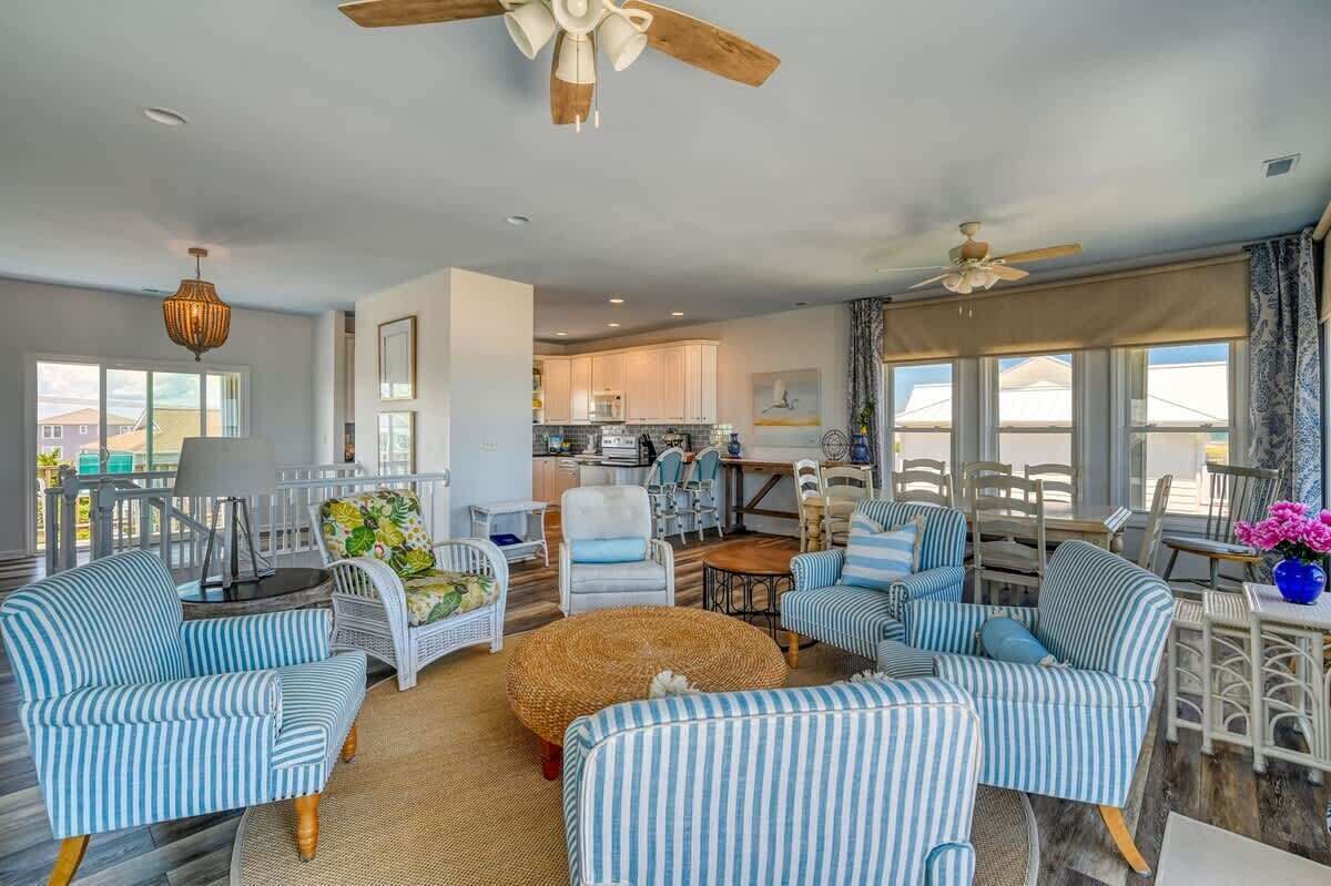 A spacious living room with striped sofas, a round coffee table, and a ceiling fan.