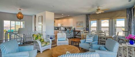 A spacious living room with striped sofas, a round coffee table, and a ceiling fan.