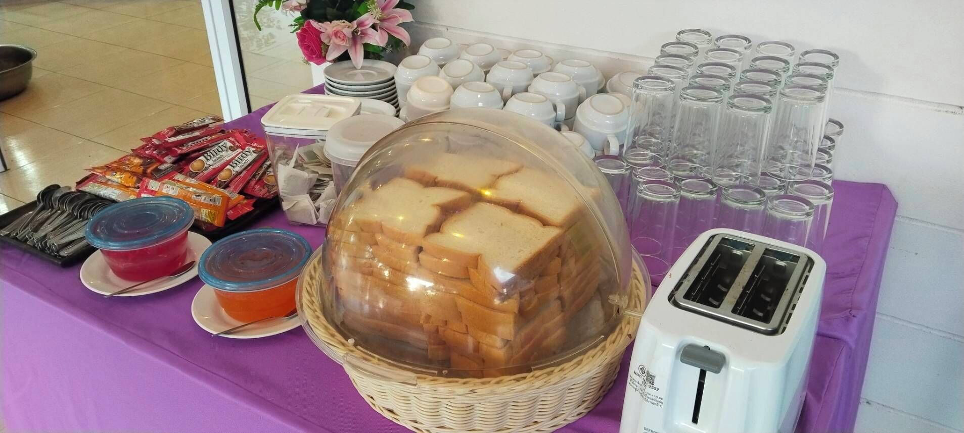A buffet table with bread, condiments, and a toaster.