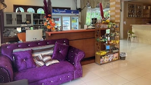 A hotel lobby with a purple sofa, a reception desk, a freezer, and a shelf with snacks. - Sukhothai Grand Hotel and Landmark (Sukhothai)