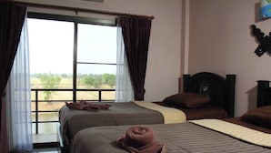A room with two beds, a view of a field through a window, and a decorative item on the wall. - Sukhothai Grand Hotel and Landmark (Sukhothai)