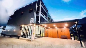A modern building with a glass entrance, a wooden reception desk, and a clear sky. - Peema Villa (U Thong)