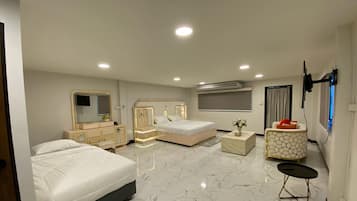A bedroom with two beds, a vanity, and a TV mounted on the wall.
