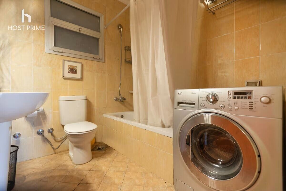Baño con inodoro, bañera y lavadora.
