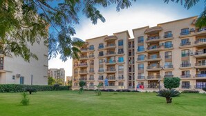 A multi-story residential building with balconies, a well-maintained lawn, and a clear sky. - Comfy Apartment in Rehab City (New Cairo)