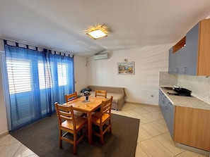 A compact living space with a dining area, kitchenette, and a sofa. - Apartment Velvet Vista 4 (Novi Vinodolski)