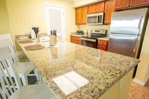 A kitchen with granite countertops, wooden cabinets, a stainless steel refrigerator, a microwave, and an oven. - Spacious 2BR Getaway at Palace View Heights with Full Resort Amenities (Branson)