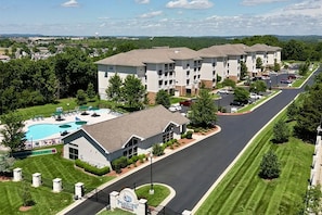 A multi-story hotel with a swimming pool, a covered patio, and a well-maintained lawn. - Spacious 2BR Getaway at Palace View Heights with Full Resort Amenities (Branson)