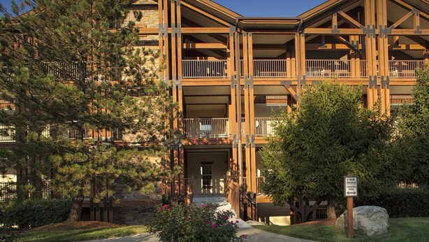Un chalet à étages avec une façade en pierre, des balcons et un ciel dégagé.