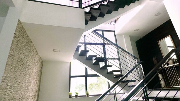 Ein modernes Interieur mit einer Wendeltreppe, großen Fenstern und einer strukturierten Wand.
