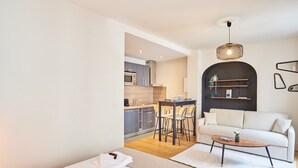 Une chambre d’hôtel moderne dotée d’une kitchenette, d’un coin repas et d’un espace de vie comprenant un canapé et une table basse.