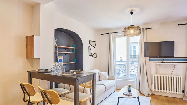 Un salon moderne comprenant un coin repas, un canapé, un téléviseur et une fenêtre avec des rideaux.