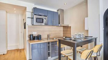 A compact kitchen with a microwave, sink, and a small dining area with stools.