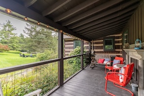 Eine überdachte Veranda mit Holzbalkonen, einem roten Sessel, einem Tisch und einer Laterne.