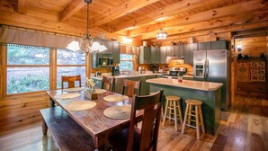 A wooden cabin interior with a dining area, kitchen, and large windows. - Garretts Getaway at Watauga Lake - Private Dock, Lakefront (Butler)