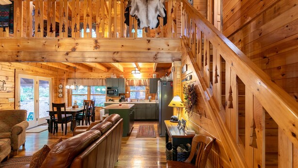 A wooden cabin interior with a dining area, kitchen, and a staircase. - Garretts Getaway at Watauga Lake - Private Dock, Lakefront (Butler)