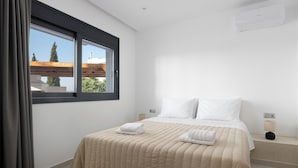 Une chambre à coucher avec un lit, une fenêtre, une table de chevet et un climatiseur fixé au mur.