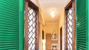 A hallway with green shutters, a tiled floor, a lamp, and a mirror on the wall. - Seaside Suite with Terrace (Marina di Massa)