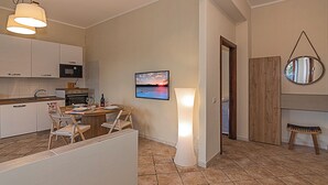 A modern kitchen with white cabinets, a microwave, and a dining area with a table set for two. - Seaside Suite with Terrace (Marina di Massa)