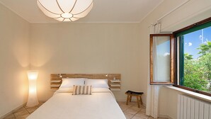 A bedroom with a bed, bedside lamps, a window with a view of greenery, and a ceiling light fixture. - Seaside Suite with Terrace (Marina di Massa)