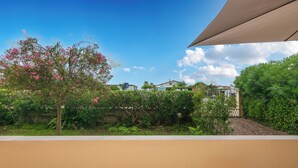 A garden with a tree bearing pink flowers, a pathway, and a building in the background. - Seaside Suite with Terrace (Marina di Massa)