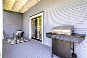 An outdoor patio with a grill, a chair, and a door. - The Laura | Entire Historic Home | Main St (Jacksonville)