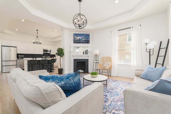A modern living room with a sofa, armchairs, a coffee table, and a fireplace.