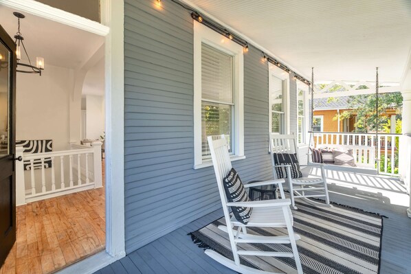 A porch with white railings, a hanging light fixture, and a striped rug.