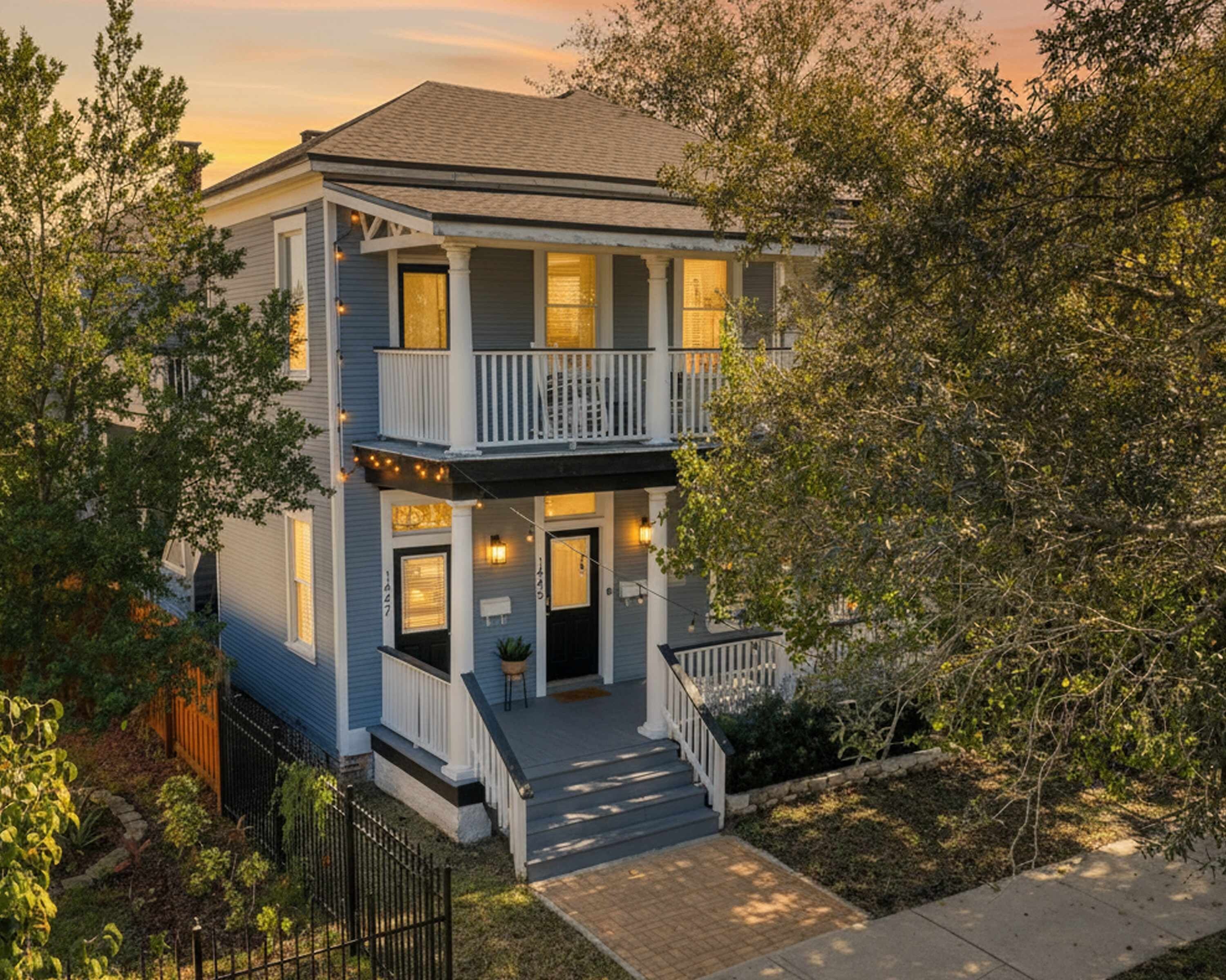 A two-story house with a front porch, a balcony, and a visible address number.