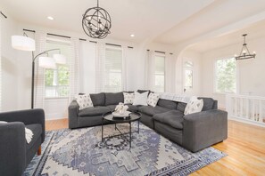 Un salon spacieux avec un canapé d’angle, une table basse et un tapis à motifs.
