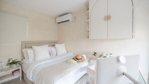 A bedroom with a bed, bedside tables, a wardrobe, an air conditioning unit, and a mirror.