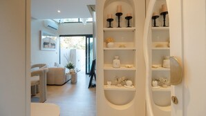 A modern interior with a sofa, a small table with a vase, and shelves with decorative items.