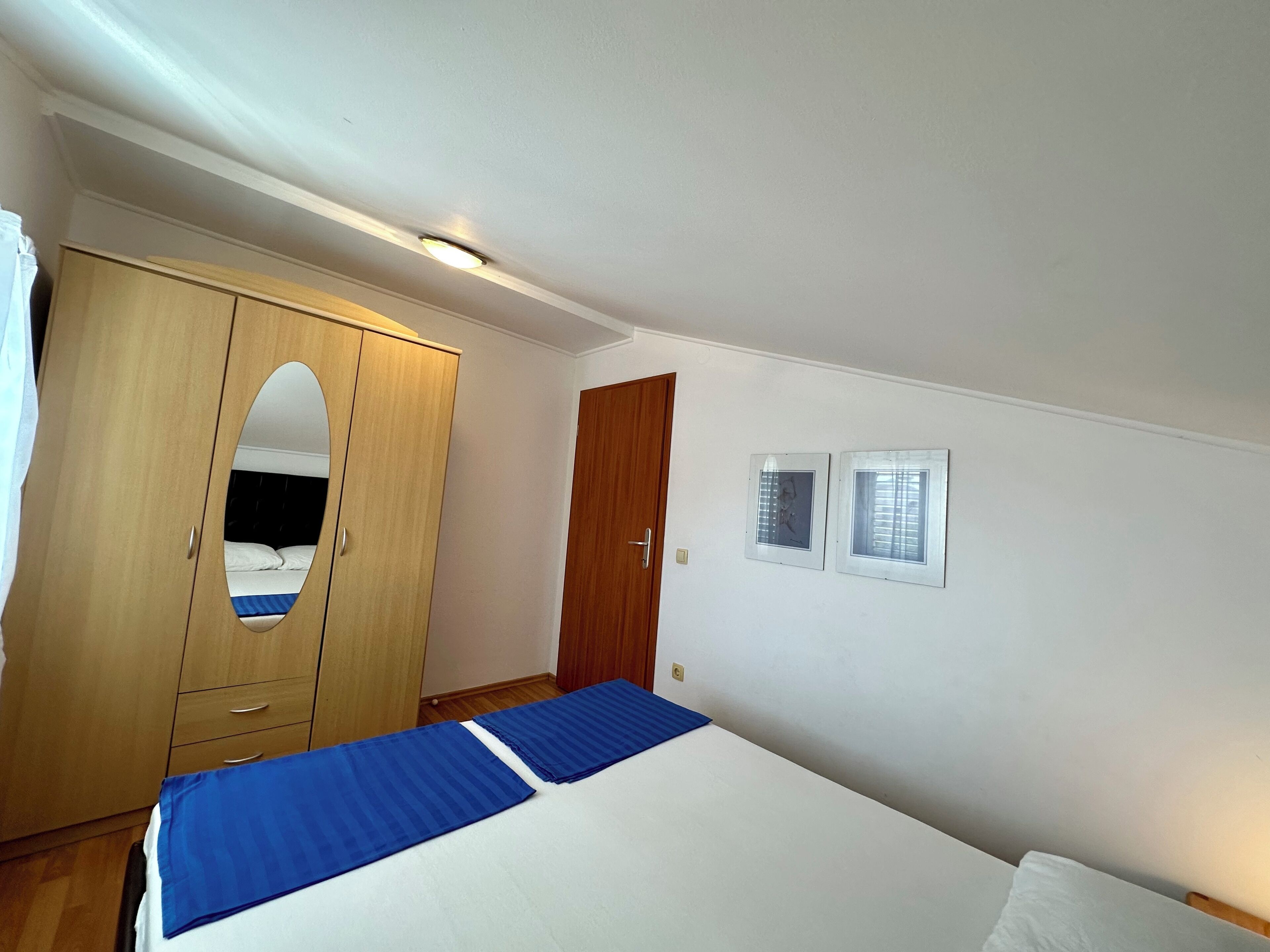 A bedroom with a bed, a wardrobe, a door, and two windows.