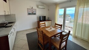 A compact kitchen with a dining area, a TV, and a view of the sea through a balcony. - Apartment Velvet Vista 5 (Novi Vinodolski)