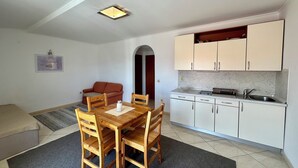 A compact living space with a dining area, kitchenette, and a sofa. - Apartment Velvet Vista 5 (Novi Vinodolski)