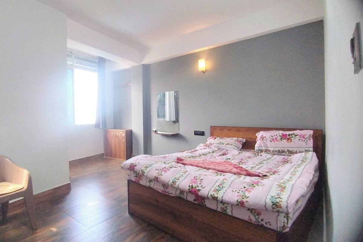 A bedroom with a wooden bed, a chair, a wardrobe, and a window.