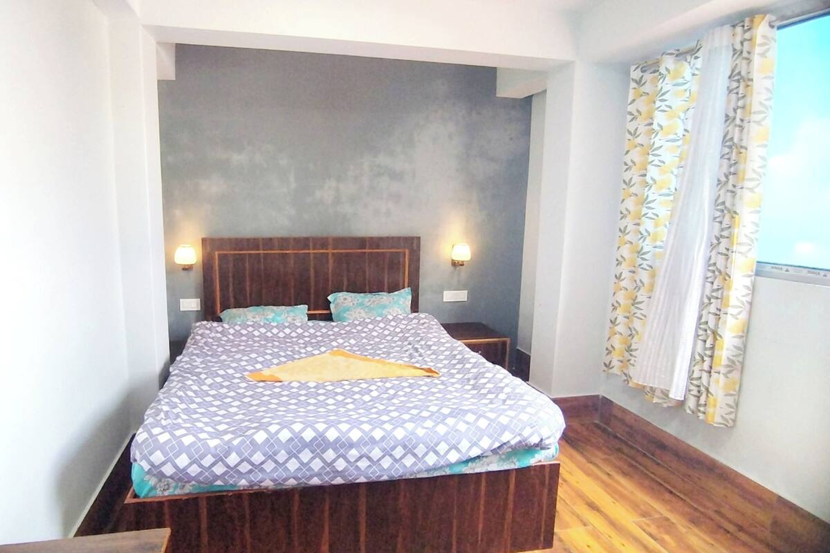 A bedroom with a large bed, two bedside tables, and a window with curtains.